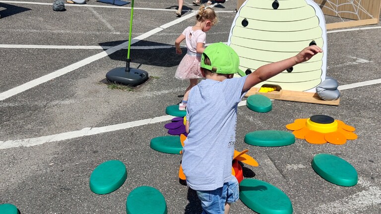 Zwei Kinder springen von Blatt zu Blatt - Station der rollenden Kinderturnwelt (Foto: Herzenssache) Zwei Kinder springen von Blatt zu Blatt - Station der rollenden Kinderturnwelt