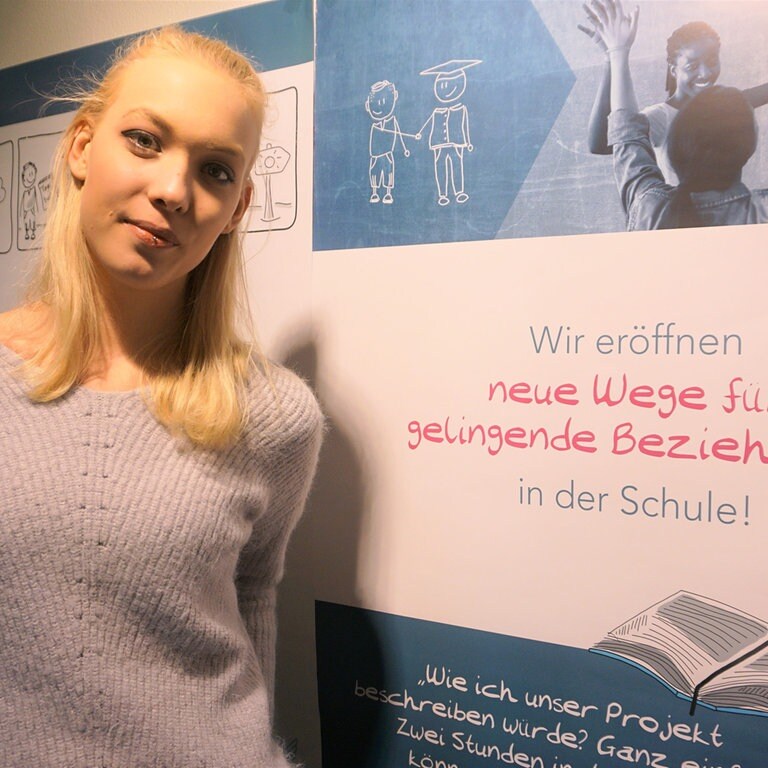Junge Frau steht vor Plakat (Foto: Herzenssache)