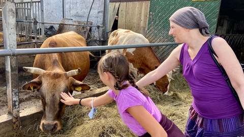 Tanja und Sophie streicheln Kühe auf einem Bauernhof (Foto: Herzenssache)
