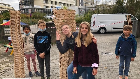 Kinder spielen vor zwei großen Türmen aus Bauklötzen. (Foto: Herzenssache)