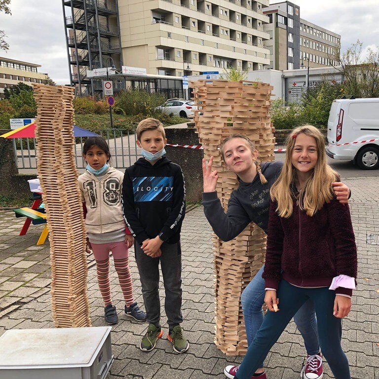 Kinder spielen vor zwei großen Türmen aus Bauklötzen. (Foto: Herzenssache)