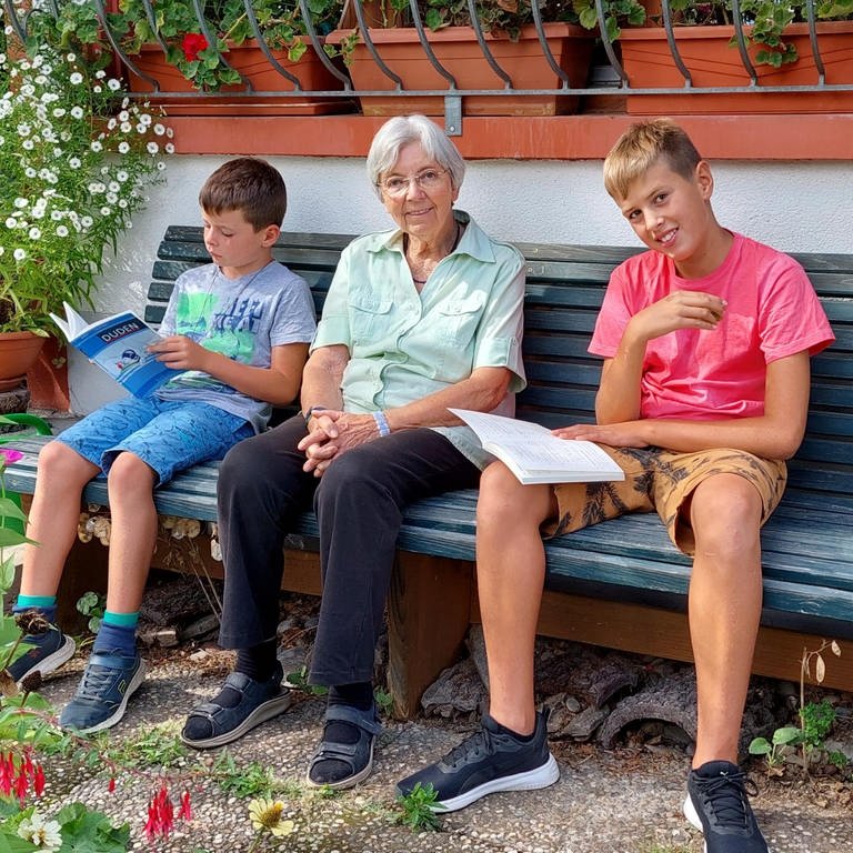 Zwei Jungs sitzen neben einer älteren Dame auf der Bank (Foto: Herzenssache e.V.)