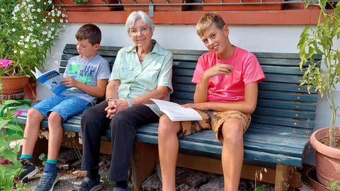 Zwei Jungs sitzen neben einer älteren Dame auf der Bank (Foto: Herzenssache e.V.)