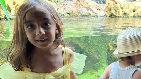 Mädchen steht vor einem Aquarium (Foto: Herzenssache e.V.)
