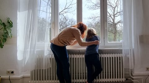 Mädchen und junge Frau schauen aus einem Fenster - nachgestellte Therapieszene (Foto: Herzenssache e.V.)