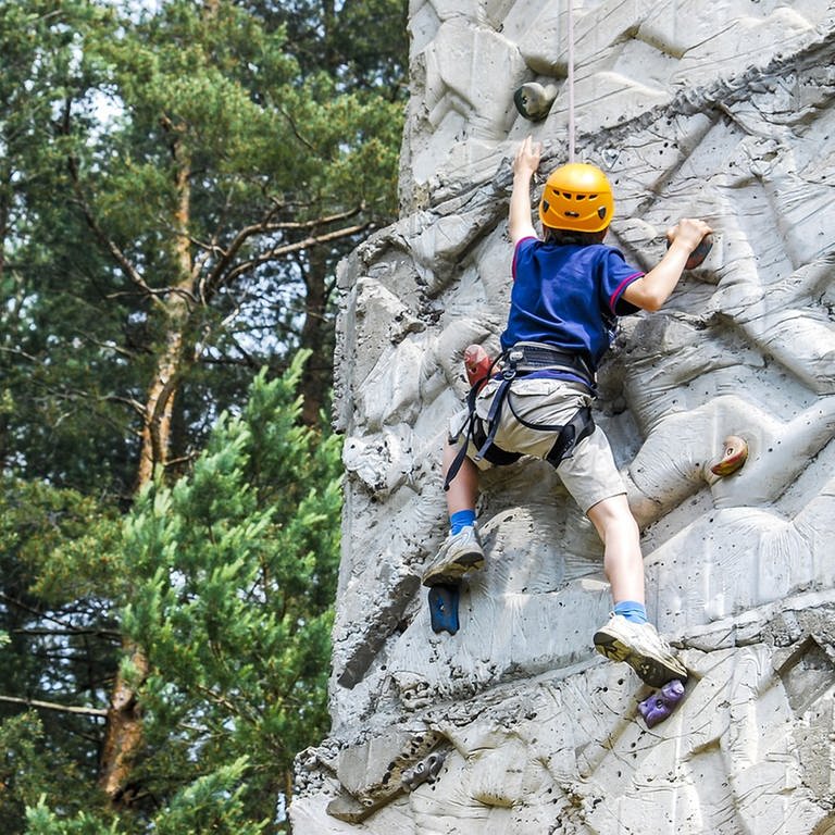 Junge im blauen Shirt klettert an einer Kletterwand (Foto: Pixabay/vrolanas)