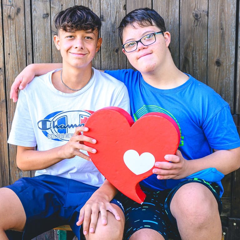Lukas (links) und Mattheo (recht, Junge mit Down Snydrom) halten das Herzenssache-Herz (Foto: Marcel Katz)