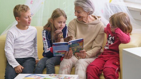 Lesepatin sitzt mit drei Kindern auf einem Sofa (Foto: Ingrid Vielsack) Lesepatin sitzt mit drei Kindern auf einem Sofa