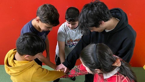 Kinder und Jugendliche stehen im Kreis, die Hände liegen in der Mitte aufeinander (Foto: Herzenssache) Kinder und Jugendliche stehen im Kreis, die Hände liegen in der Mitte aufeinander