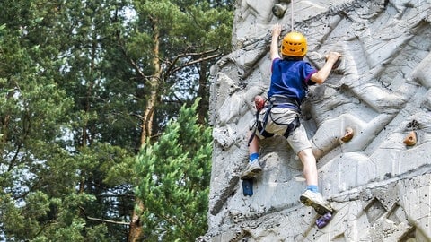 Junge im blauen Shirt klettert an einer Kletterwand (Foto: Pixabay/vrolanas)