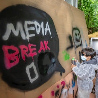 Zwei Jungs besprühen eine Leinwand