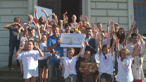 Harmut Engler nimmt Spendenscheck unter Jubel der "kleinen Stars mit Handicap" entgegen