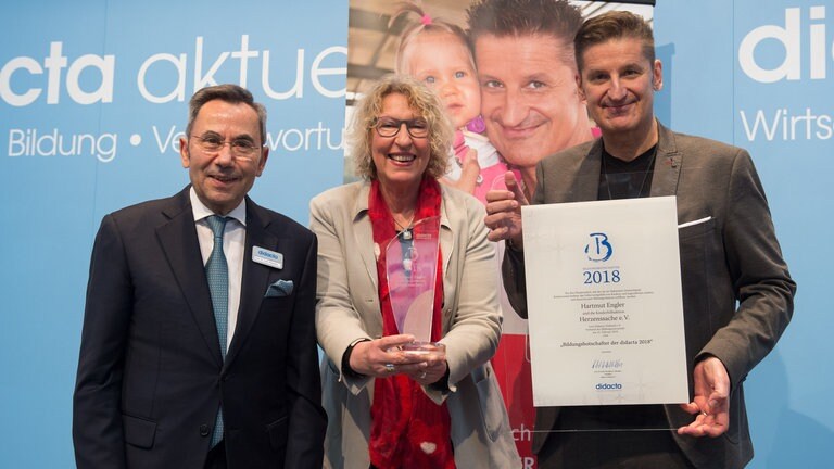 Hartmut Engler und Gitta Haucke von Herzenssache freuen sich über die Bildungsbotschafter Auszeichnung von Didacta Präsident Prof. Dr. mult. Fthenakis. (Foto: Deutsche Presse)