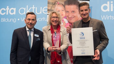 Hartmut Engler und Gitta Haucke von Herzenssache freuen sich über die Bildungsbotschafter Auszeichnung von Didacta Präsident Prof. Dr. mult. Fthenakis. (Foto: Deutsche Presse)